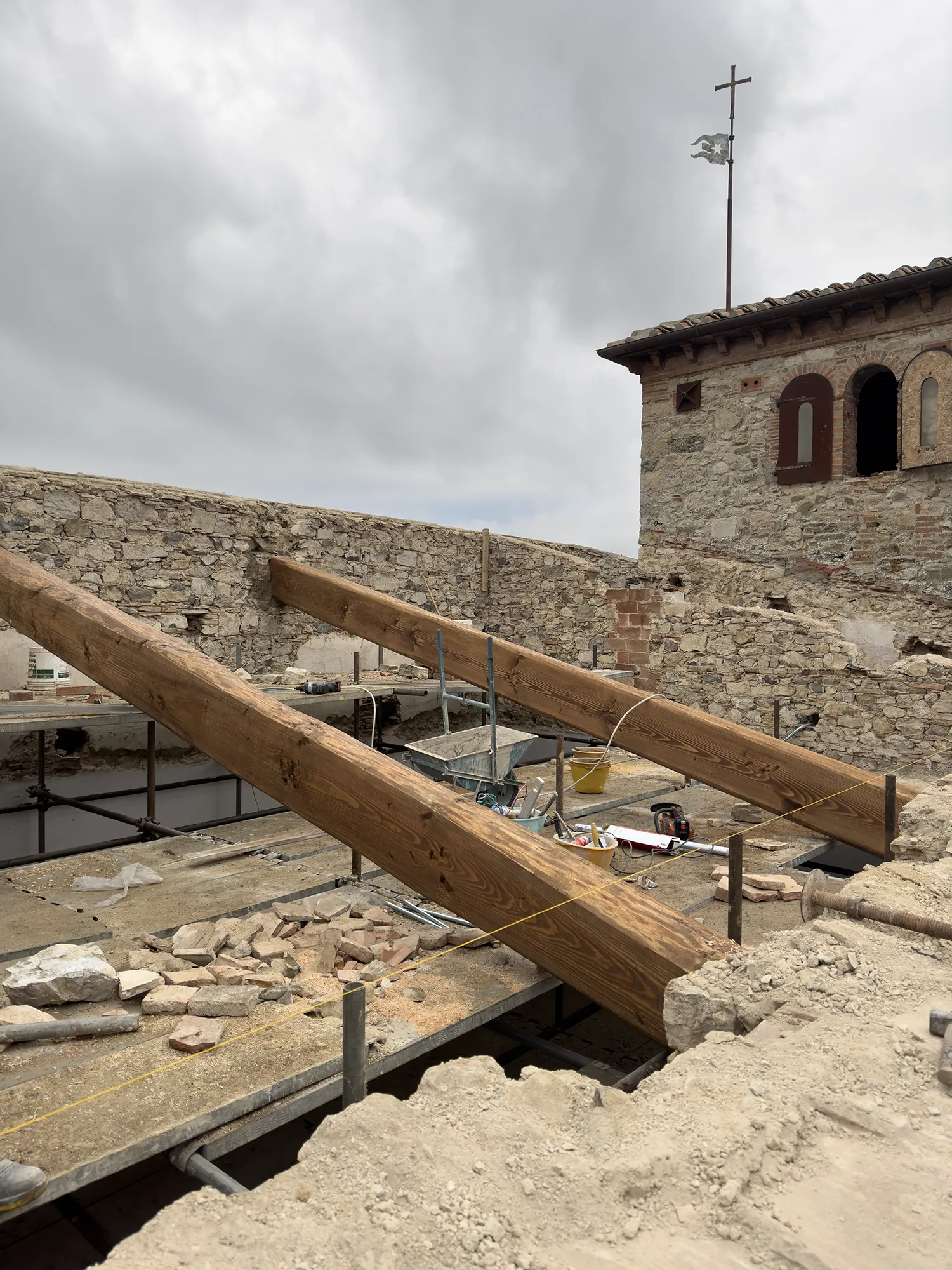 Grandi travi in legno posizionate sulle storiche murature in pietra nuda durante le delicate fasi di consolidamento strutturale eseguite da MC Moretti
